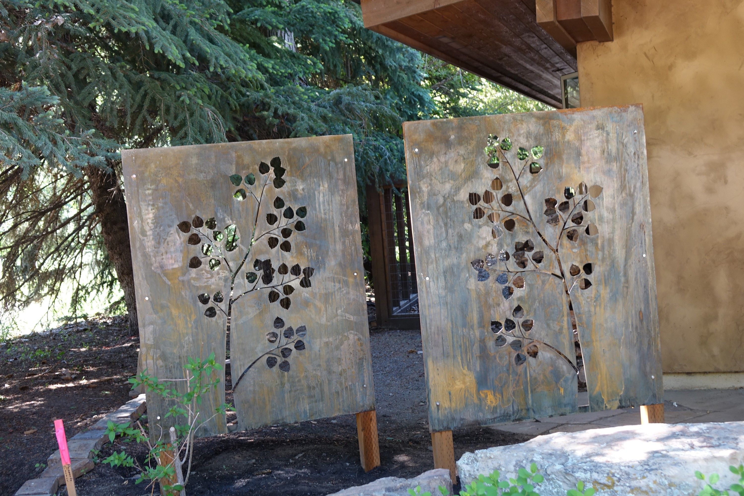 The two panels from closer in, the cut-out leaves opening onto the trees and the path behind them