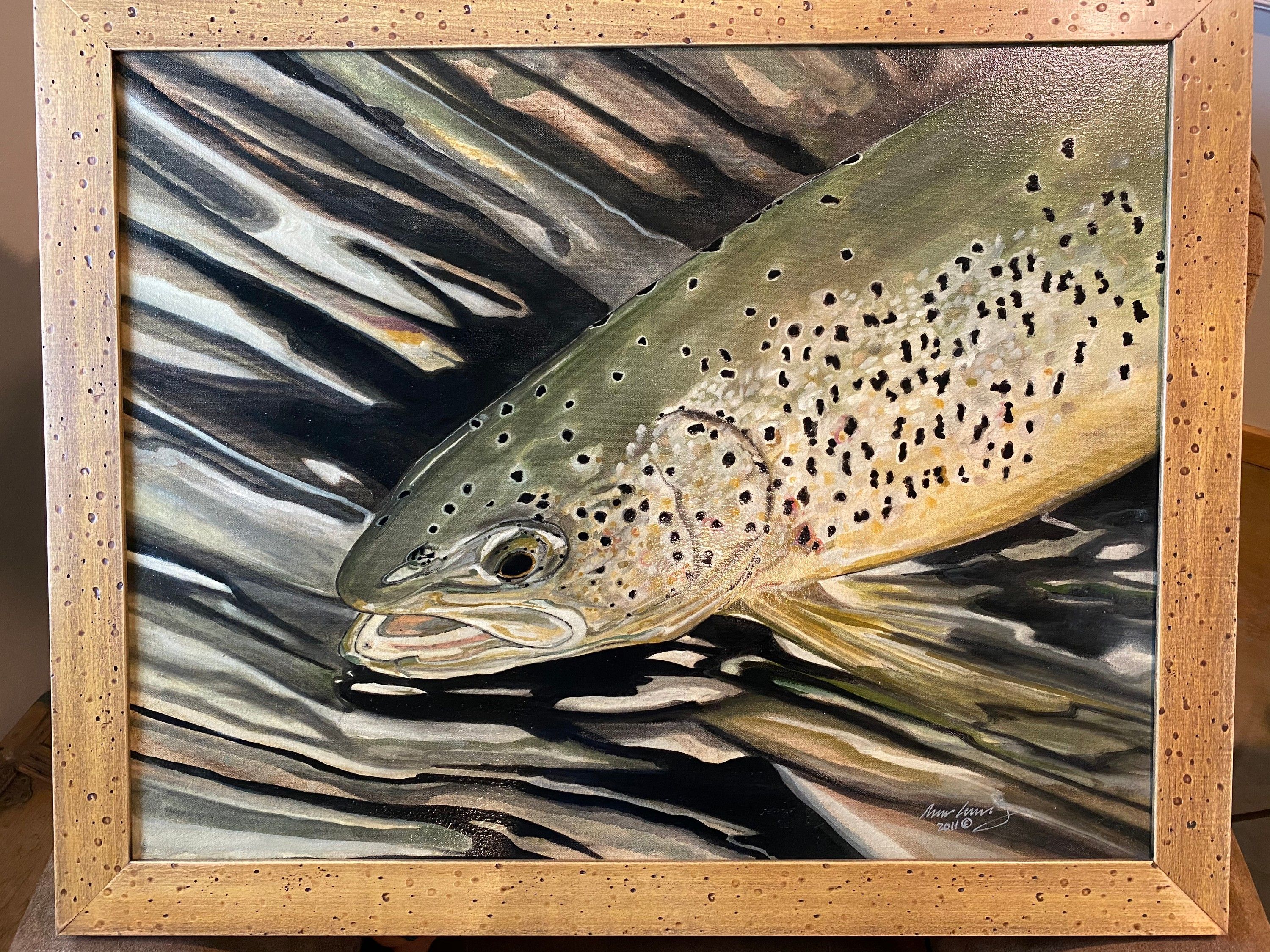 A painting of a spotted trout just under the surface of clear moving water, in a pale wooden frame, signed in the lower right corner