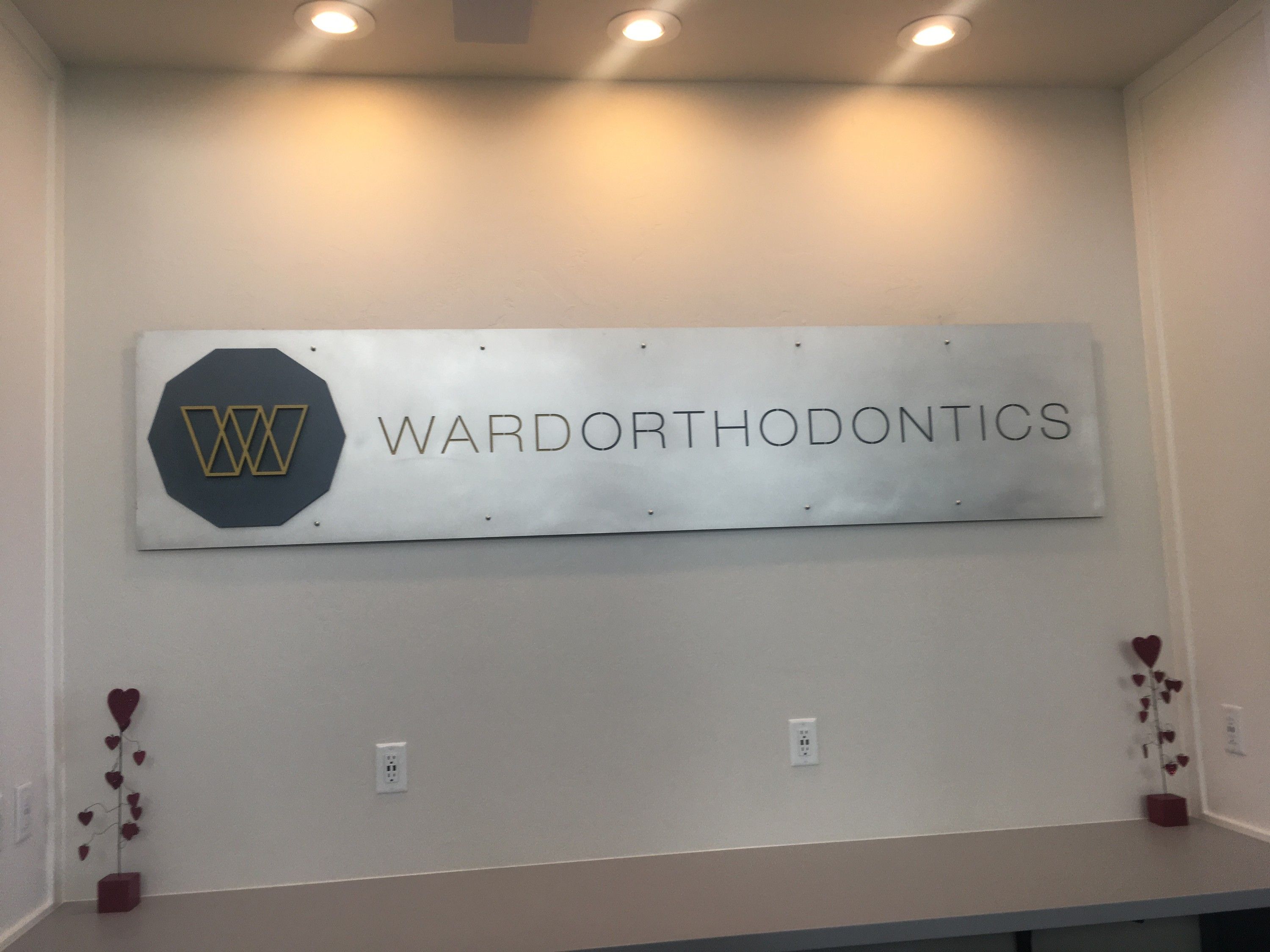 The Ward Orthodontics sign installed on the clinic wall, lit from above