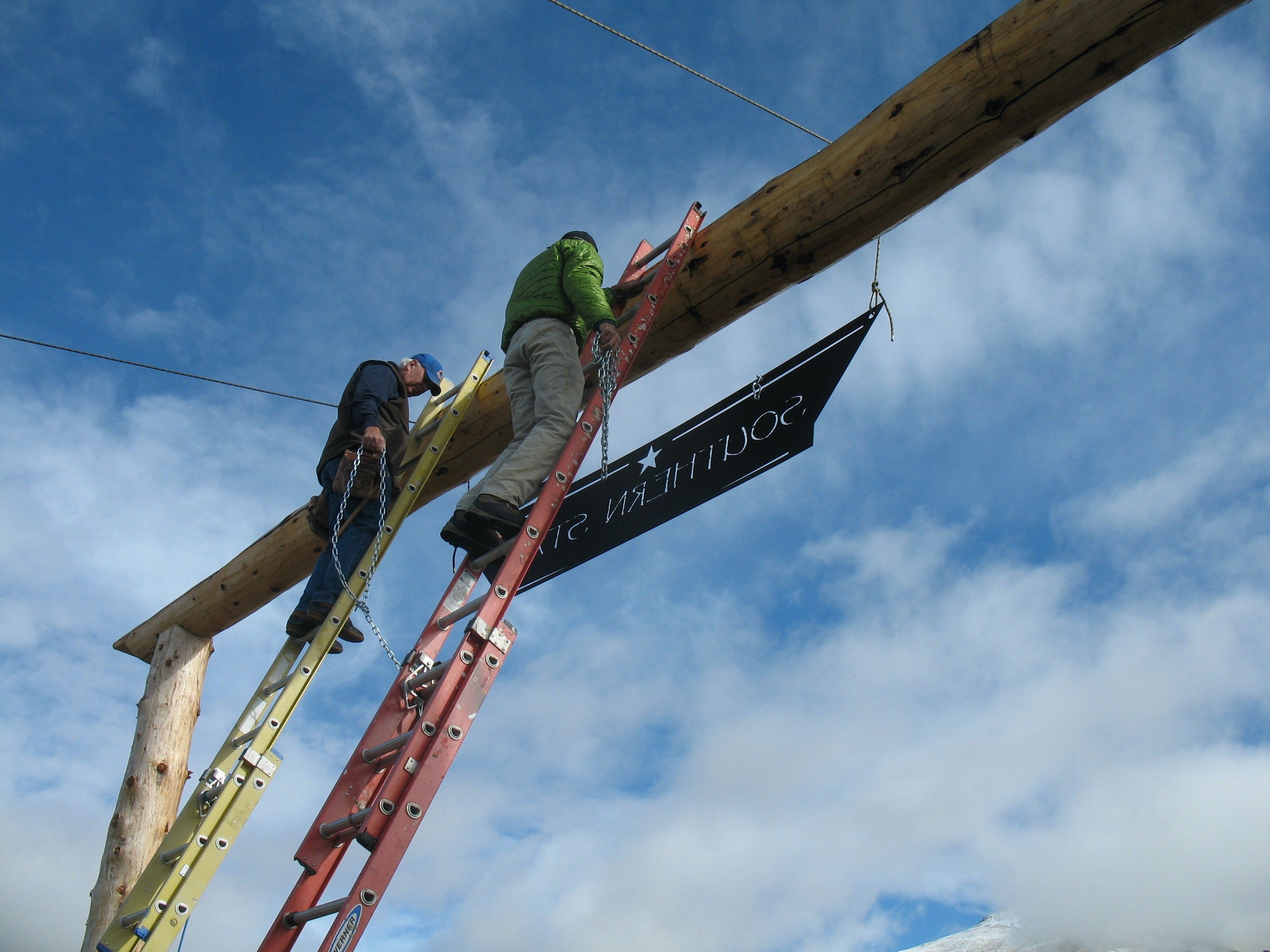 Russ Lamb and a helper on ladders hanging the Southern Star sign from the entrance beam
